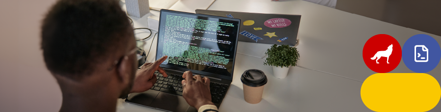 Person working on a laptop with code displayed on the screen, coffee cup and potted plant on desk.

